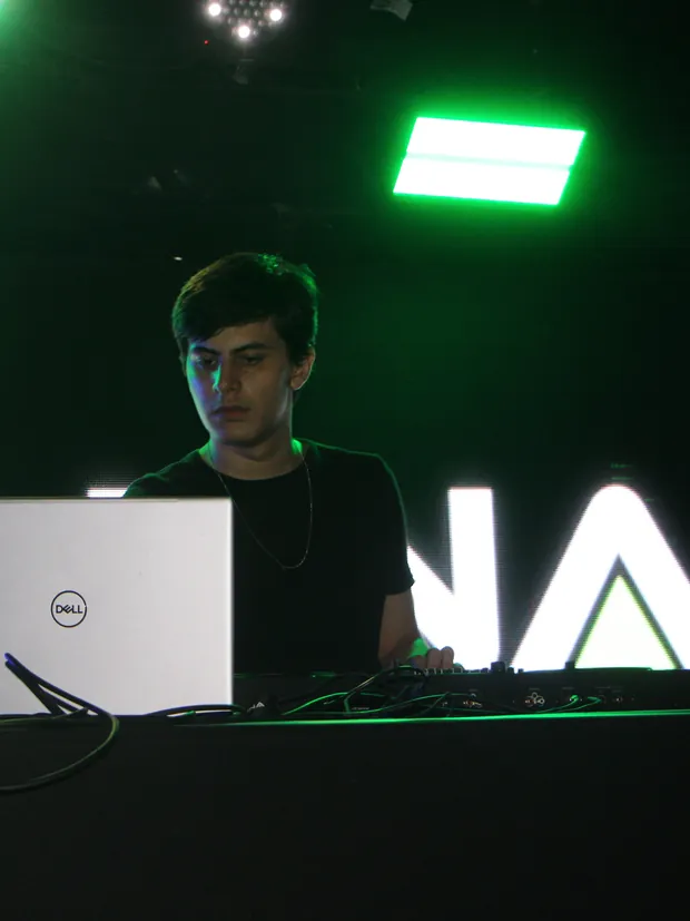 VELUNA tocando no palco, com o logotipo VELUNA no painel de LED e luzes verdes ao fundo