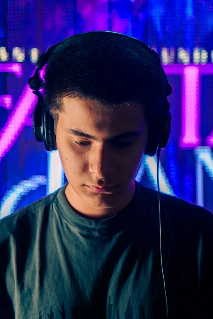 Pedro, o VELUNA, de fones, diante de um painel de luz violeta